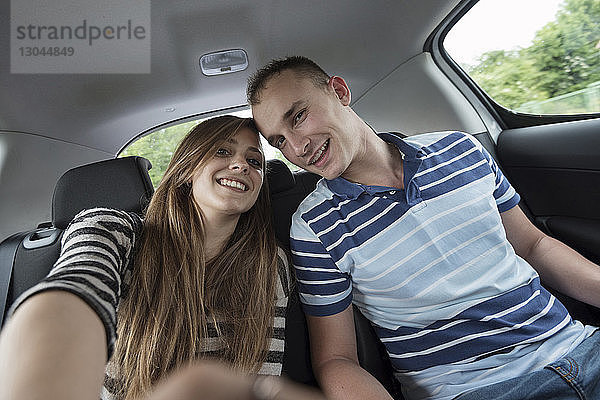 Porträt eines glücklichen Paares  das im Urlaub im Auto sitzt