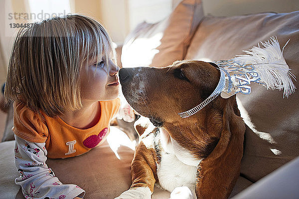 Mädchen liegt mit Hund zu Hause auf dem Sofa