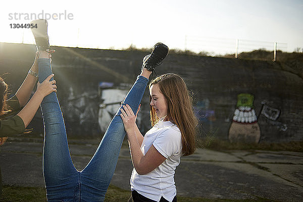 Verspielte Freunde halten Teenager-Mädchen an den Beinen