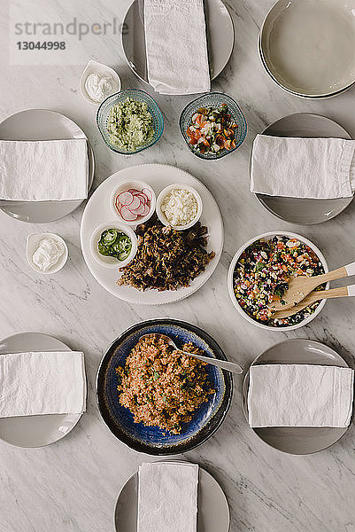 Hochwinkelansicht von Lebensmitteln mit Tellern und Papiertaschentüchern auf dem Tisch