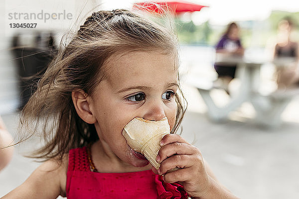 Süßes Mädchen schaut weg  während es im Straßencafé Eis isst
