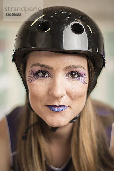 Porträt einer selbstbewussten  geschminkten Sportlerin mit Helm beim Roller-Derby