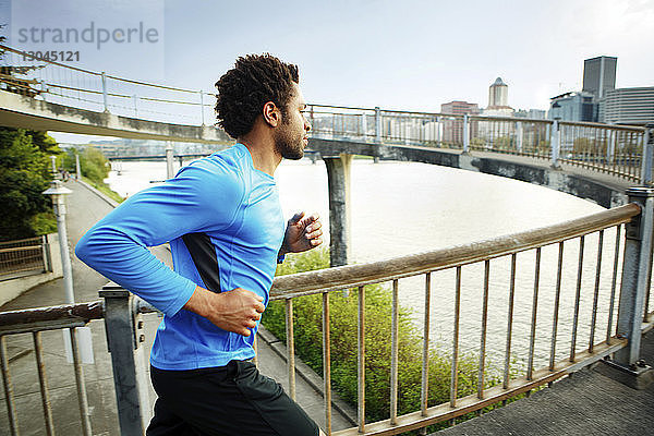 Männlicher Athlet joggt auf einer Brücke in der Stadt