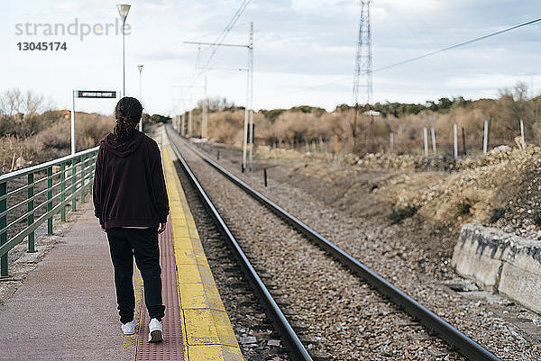 Rückansicht in voller Länge eines Teenager-Mädchens  das auf dem Bahnsteig des Bahnhofs läuft