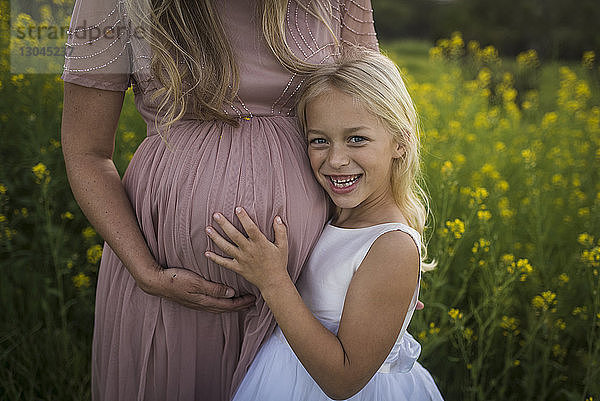 Mittelsektion einer schwangeren Mutter mit glücklicher Tochter im Park