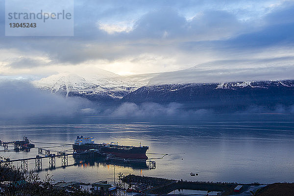 Hochwinkelansicht der Silhouette eines im Hafen vor Anker liegenden Supertankers vor bewölktem Himmel