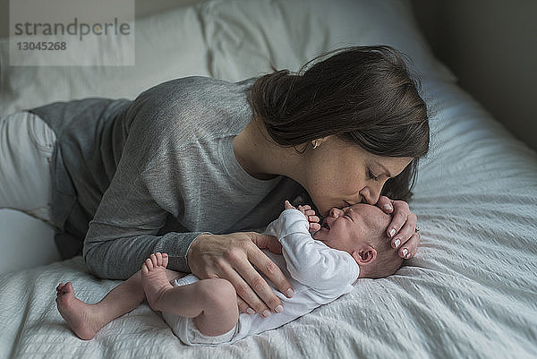 Hochwinkelaufnahme einer Mutter  die ein schreiendes Neugeborenes auf die Stirn küsst