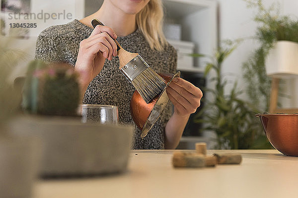 Mittelteil einer Geschäftsfrau  die eine Metallschüssel bürstet  um ein Büro aus Betontopf zu machen