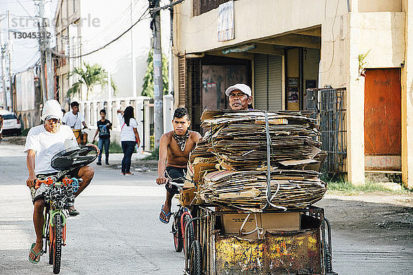 Mann trägt einen Stapel Pappe auf einem Dreirad in der Stadt