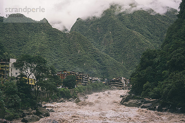 Überschwemmung im Fluss durch Gebäude inmitten von Bergen