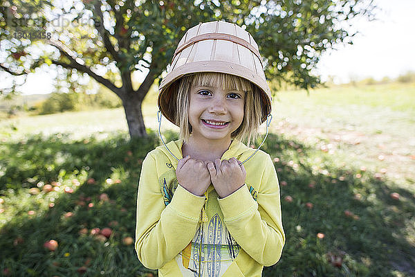 Porträt eines glücklichen Mädchens auf einem Bauernhof an einem Apfelbaum stehend