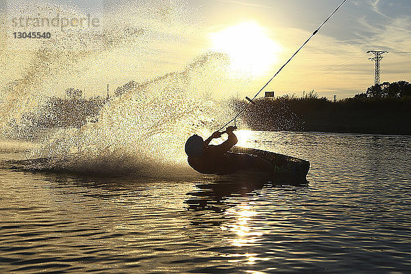 Silhouette eines Mannes beim Kitesurfen auf dem See