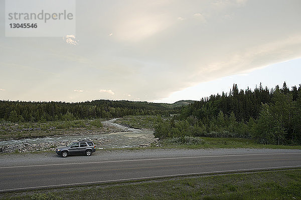 Hochwinkelaufnahme eines auf der Landstraße im Glacier National Park geparkten Geländewagens
