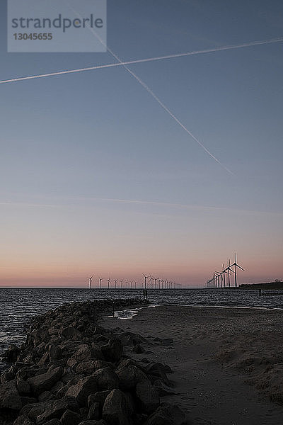 Schattenrisse von Windmühlen auf dem Meer gegen den Himmel bei Sonnenuntergang