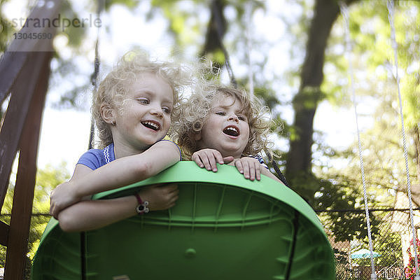 Niedrigwinkelansicht von Schwestern  die auf Außenspielgeräten auf dem Spielplatz spielen