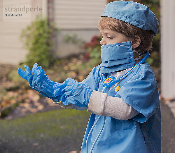 Junge in Arztkostüm mit Handschuhen  während er im Hof steht