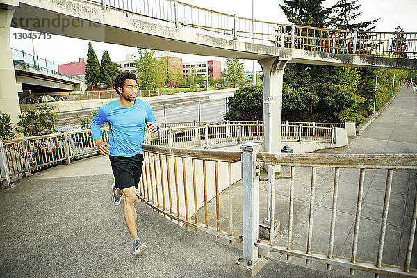 Männlicher Athlet joggt auf der Brücke