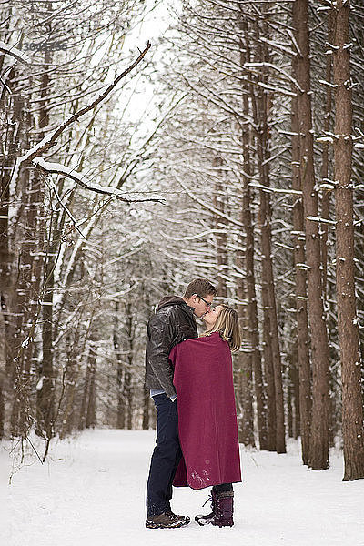 Seitenansicht eines Paares  das sich küsst  während es auf einem schneebedeckten Feld steht