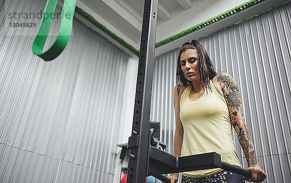 Niedrigwinkelansicht eines Athleten  der auf einem Dip-Gerät im Fitnessstudio trainiert