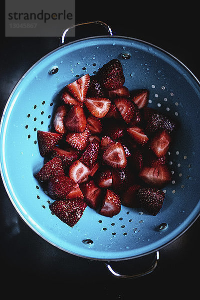 Draufsicht auf gewaschene  in Scheiben geschnittene Erdbeeren im Sieb