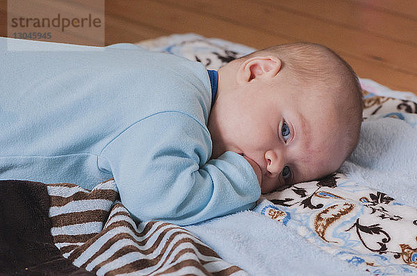 Süßer kleiner Junge liegt zu Hause auf einer Decke