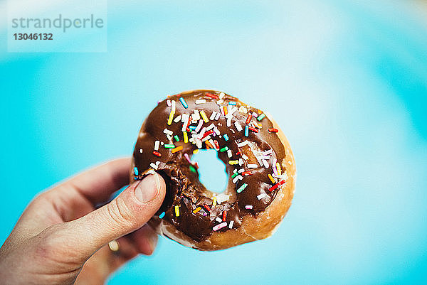 Abgehackte Hand einer Person  die einen Donut hält