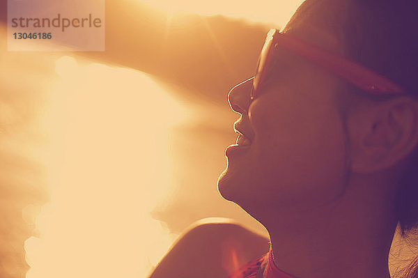 Nahaufnahme einer glücklichen Frau mit Sonnenbrille  die auf den Strand schaut