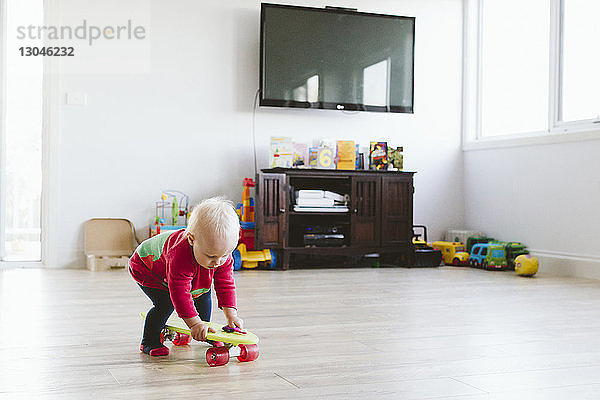 Verspieltes Mädchen  das zu Hause mit dem Skateboard spielt