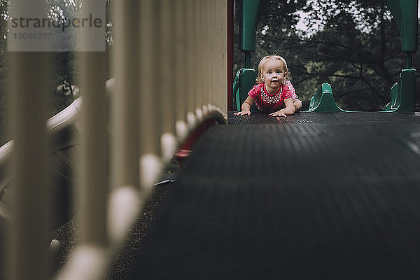 Porträt eines kleinen Mädchens auf einer Rutsche auf einem Spielplatz