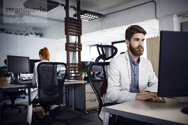 Geschäftsmann mit Desktop-Computer im Kreativbüro
