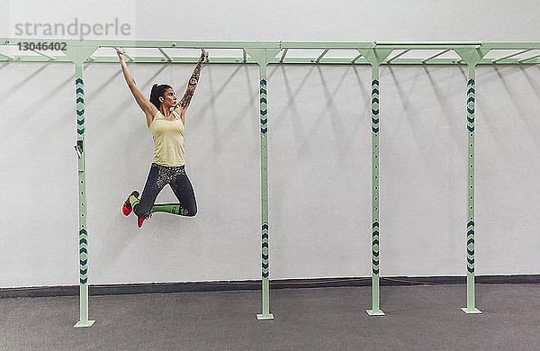 Sportler  der im Fitnessstudio an Affenstangen hängt