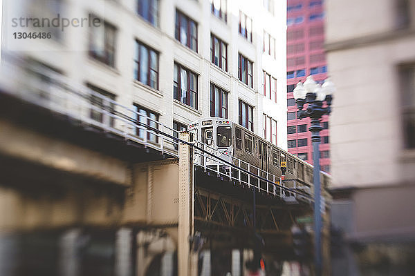 Niedrigwinkelansicht eines Zuges  der auf einer Eisenbahnbrücke in der Stadt fährt