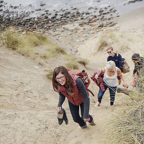 Glückliche Frau geht mit Freunden am Strand im Sand spazieren