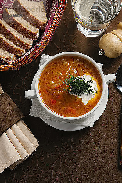 Schrägaufnahme einer Suppe in einer Schüssel mit Broten und Getränken  die auf dem Tisch serviert werden