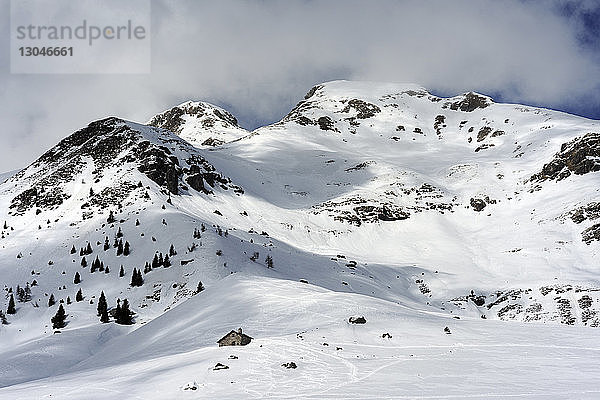 Tiefwinkelansicht eines schneebedeckten Berges vor bewölktem Himmel