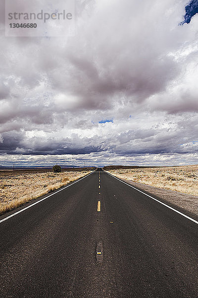 Landstraße mitten im Feld gegen Gewitterwolken