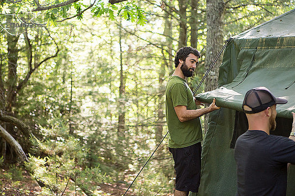 Männliche Wanderer beim Zelten auf einem Campingplatz im Wald