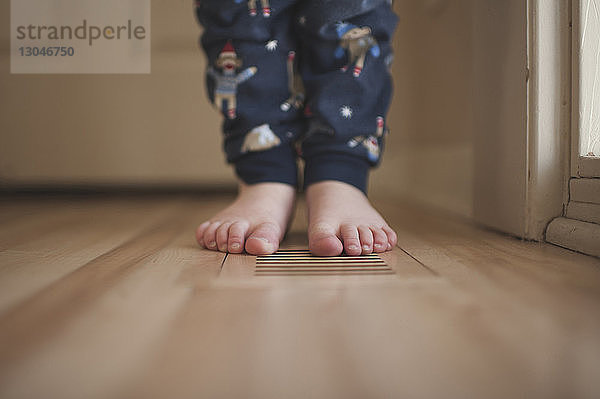 Niedriger Teil eines Jungen  der zu Hause auf dem Boden steht