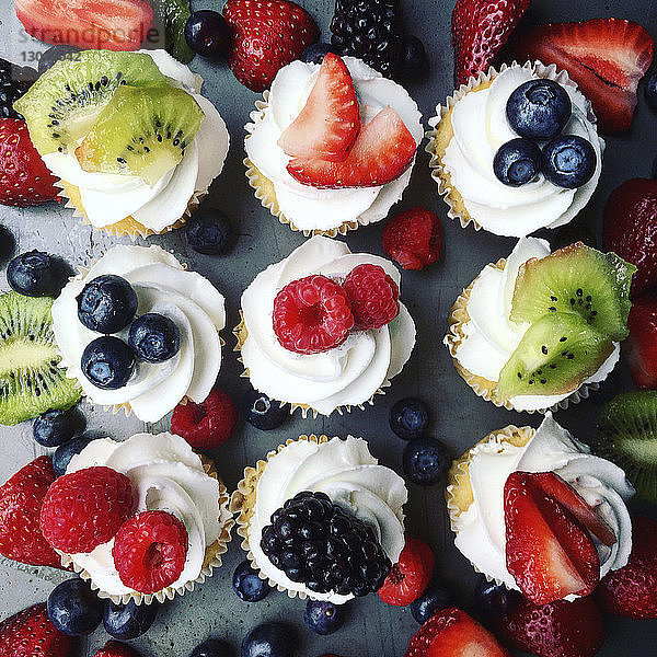 Draufsicht auf mit Früchten garnierte Cupcakes auf dem Tisch