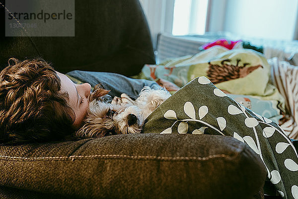 Junge und Hund schlafen zu Hause auf dem Sofa