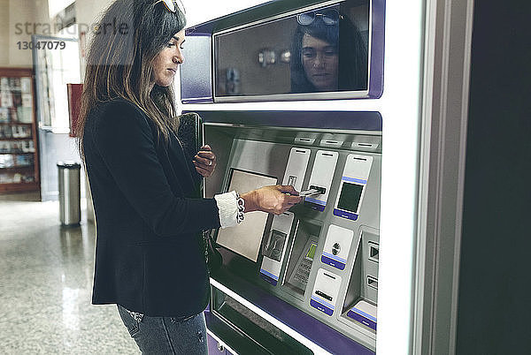 Frau schiebt Karte in Geldautomaten ein