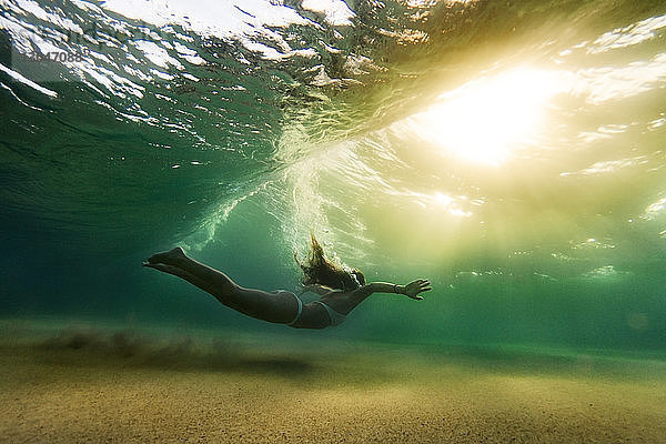 Seitenansicht einer Frau im Bikini  die unter Wasser schwimmt