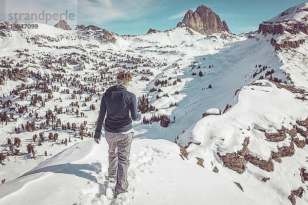 Rückansicht einer Frau  die auf einem verschneiten Feld im Grand-Teton-Nationalpark läuft