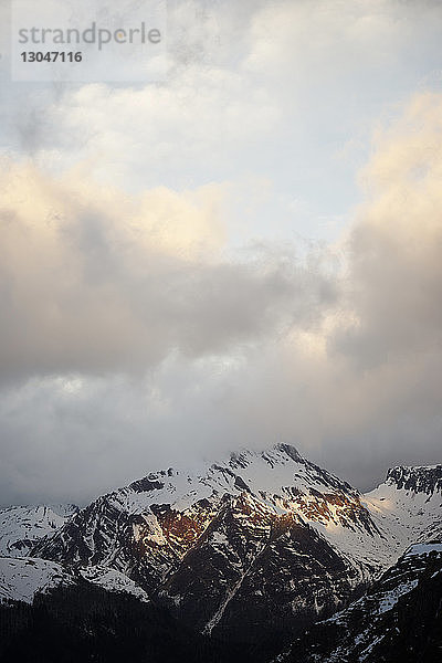 Blick auf schneebedeckte Berge vor bewölktem Himmel