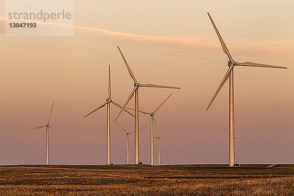 Windturbinen auf dem Feld gegen den Himmel bei Sonnenuntergang