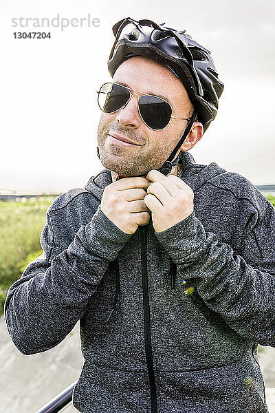 Porträt eines Mannes mit Fahrradhelm vor klarem Himmel