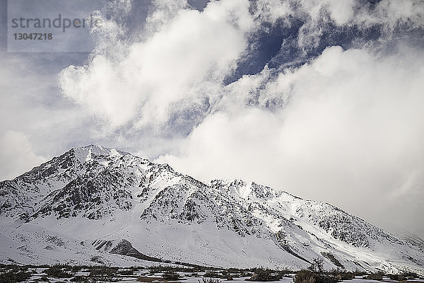 Szenische Ansicht eines schneebedeckten Berges vor bewölktem Himmel