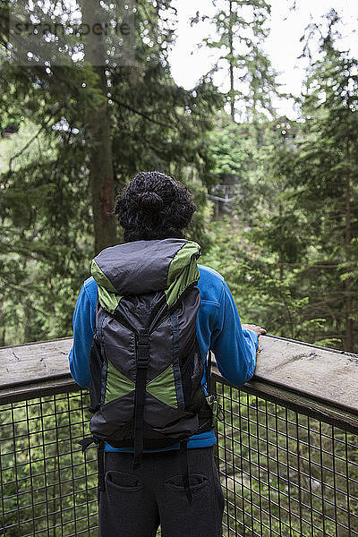 Wanderer mit Rucksack beim Blick in den Wald