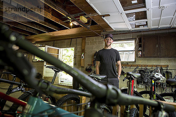 Niedrigwinkel-Porträt eines selbstbewussten Mechanikers mit Händen in den Taschen im Fahrradladen stehend