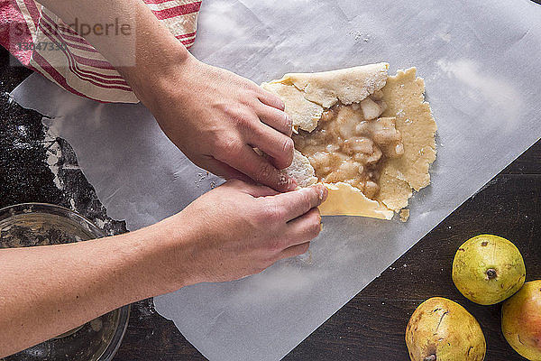 Beschnittenes Bild von Händen  die bei Tisch Guavenkuchen machen